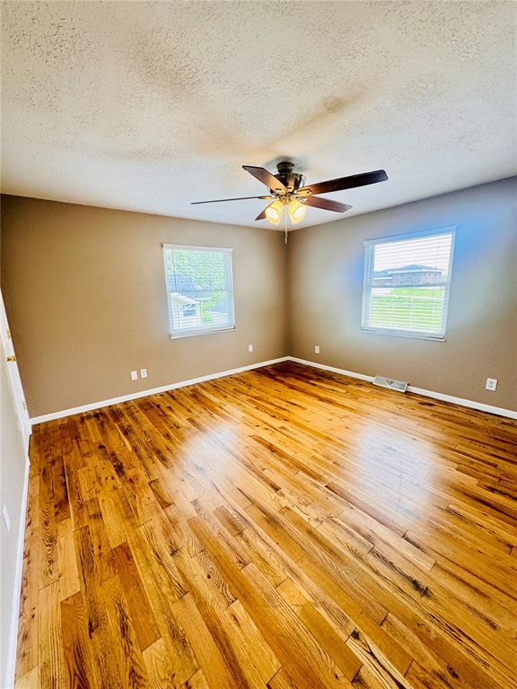 1202 S Mildred Ave, Salem, MO 65560 - empty room with a textured ceiling, wood finished floors, plenty of natural light, and ceiling fan
