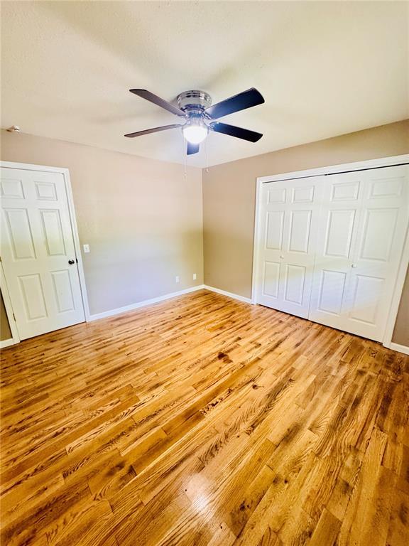 1202 S Mildred Ave, Salem, MO 65560 - unfurnished bedroom featuring wood finished floors, baseboards, ceiling fan, and a closet