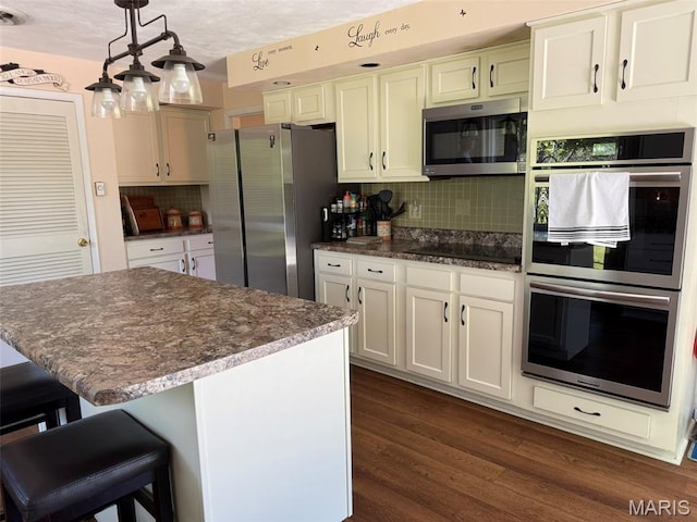 414 Hillcrest Dr, Sullivan, MO 63080 - kitchen featuring appliances with stainless steel finishes, tasteful backsplash, dark wood-style floors, decorative light fixtures, and a breakfast bar