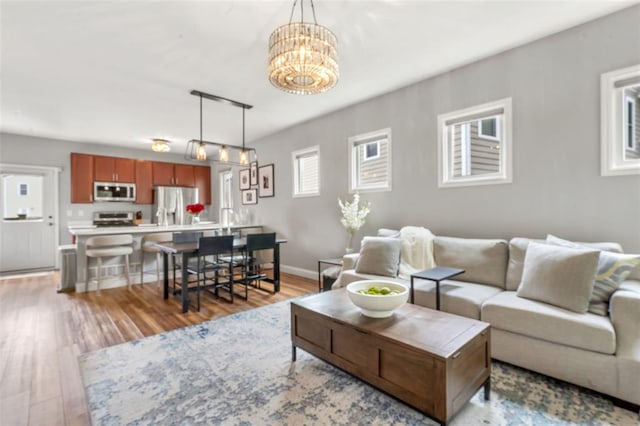 3481 New Town Lake Dr, Saint Charles, MO 63301 - living room featuring light wood-type flooring, a chandelier, and baseboards