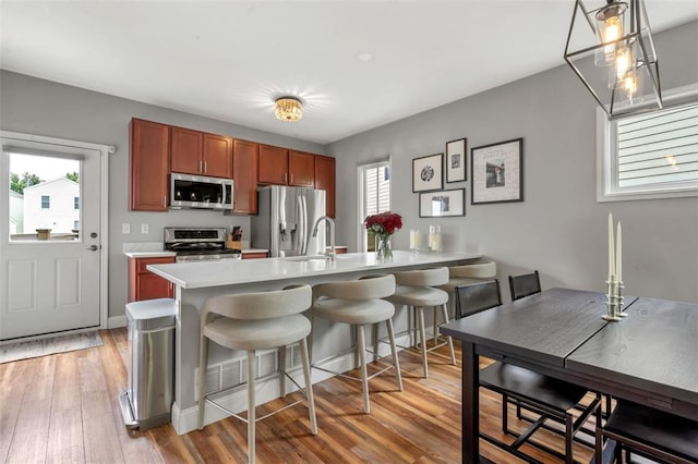 3481 New Town Lake Dr, Saint Charles, MO 63301 - kitchen featuring appliances with stainless steel finishes, light countertops, a peninsula, a breakfast bar area, and light wood-style floors