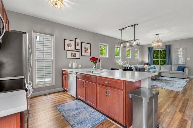 3481 New Town Lake Dr, Saint Charles, MO 63301 - kitchen with stainless steel appliances, a peninsula, a sink, light wood finished floors, and light countertops