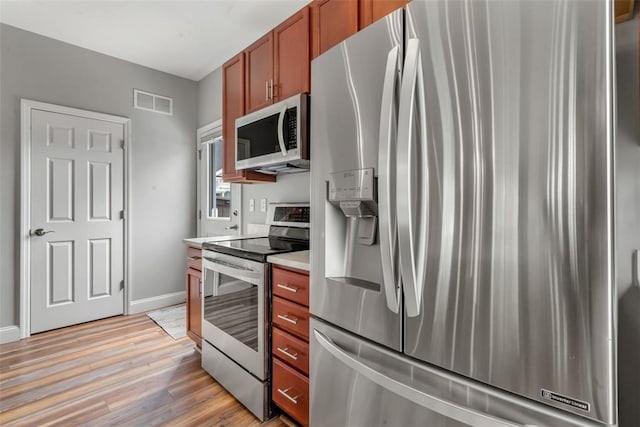3481 New Town Lake Dr, Saint Charles, MO 63301 - kitchen with appliances with stainless steel finishes, light wood-type flooring, light countertops, baseboards, and brown cabinetry