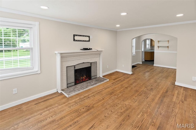 6446 Old Collinsville Rd, Ofallon, IL 62269 - unfurnished living room featuring crown molding, a fireplace, wood finished floors, recessed lighting, and arched walkways