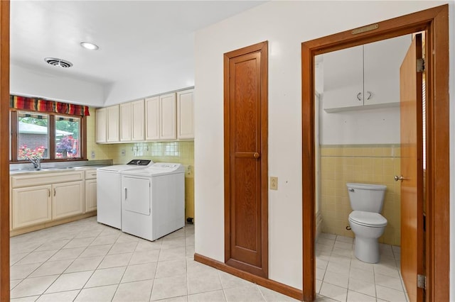814 Pardee Rd, Godfrey, IL 62035 - laundry area featuring independent washer and dryer, light tile patterned floors, cabinet space, tile walls, and wainscoting