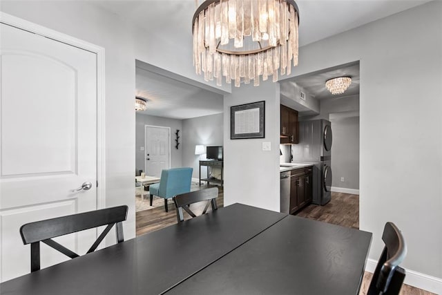 1491 Bobolink Pl, Brentwood, MO 63144 - dining space featuring stacked washing machine and dryer, a chandelier, dark wood-style floors, and baseboards