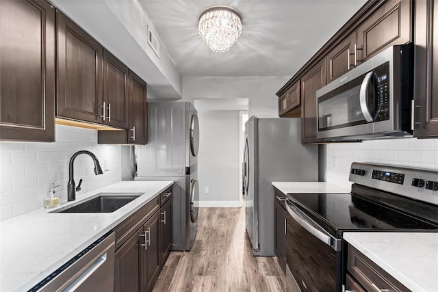 1491 Bobolink Pl, Brentwood, MO 63144 - kitchen featuring stainless steel appliances, stacked washer / drying machine, a sink, dark brown cabinets, and light wood-type flooring