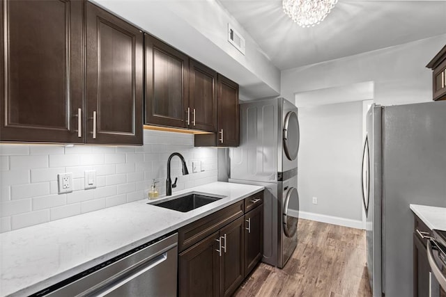 1491 Bobolink Pl, Brentwood, MO 63144 - kitchen with a sink, stacked washer / drying machine, stainless steel appliances, light wood-style flooring, and dark brown cabinetry
