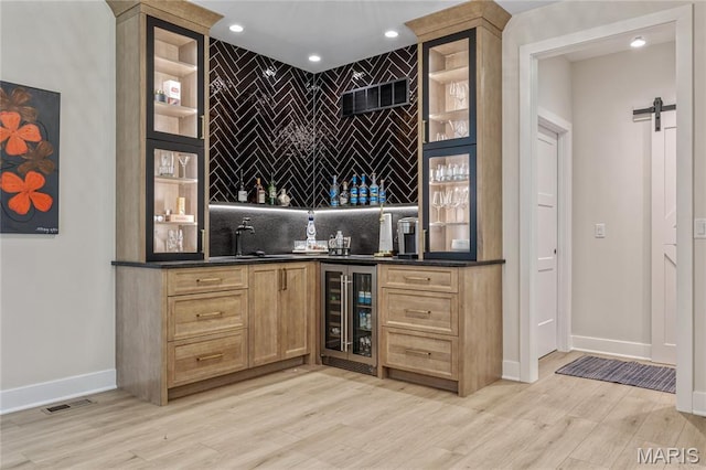 100 Enclave Terrace Ct, Weldon Spring, MO 63304 - indoor wet bar featuring beverage cooler, light wood-type flooring, baseboards, decorative backsplash, and recessed lighting