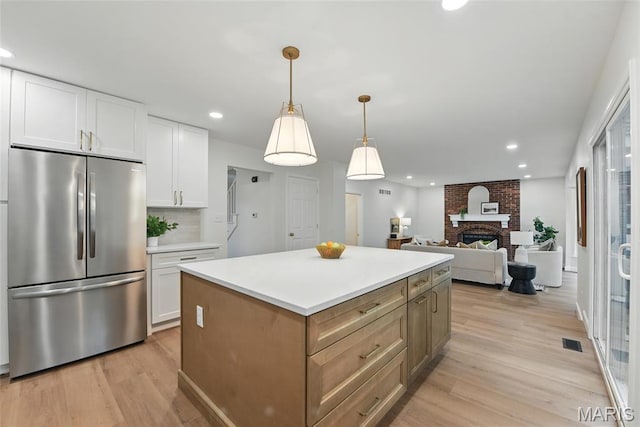 973 Kylemore Dr, Ballwin, MO 63021 - kitchen featuring freestanding refrigerator, light wood-type flooring, white cabinets, a fireplace, and recessed lighting