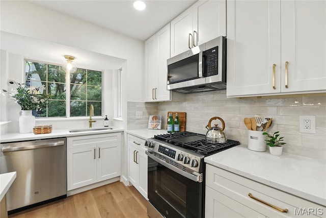 973 Kylemore Dr, Ballwin, MO 63021 - kitchen with appliances with stainless steel finishes, a sink, white cabinets, light countertops, and light wood finished floors