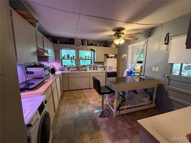 929 Race St, Thayer, MO 65791 - kitchen featuring washer / clothes dryer, under cabinet range hood, a ceiling fan, light countertops, and plenty of natural light