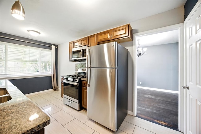 7448 Ahern Ave, Saint Louis, MO 63130 - kitchen featuring appliances with stainless steel finishes, brown cabinets, baseboards, light stone counters, and light tile patterned flooring