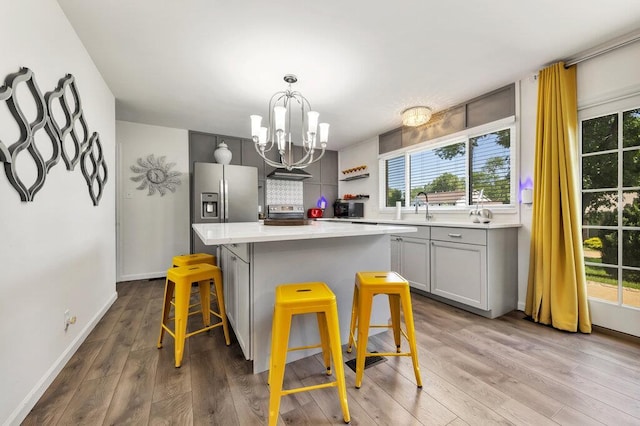 11943 Brookington Dr, Bridgeton, MO 63044 - kitchen featuring a breakfast bar area, a chandelier, a kitchen island, gray cabinets, and stainless steel appliances