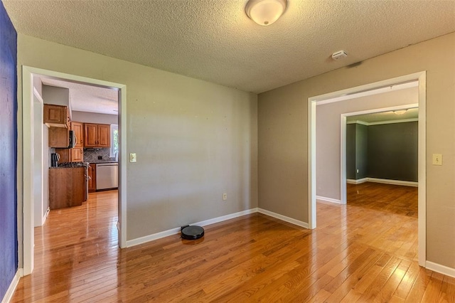 21509 Rockwell Dr, Lebanon, MO 65536 - empty room featuring light wood-style floors, a textured ceiling, baseboards, and a smoke detector