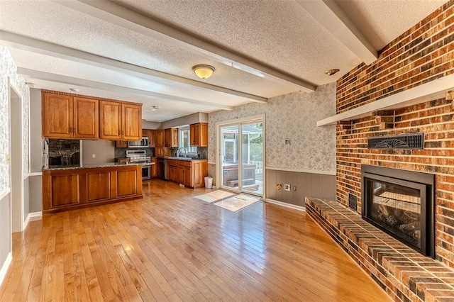 21509 Rockwell Dr, Lebanon, MO 65536 - kitchen with brown cabinets, appliances with stainless steel finishes, a sink, wainscoting, and light wood-style flooring