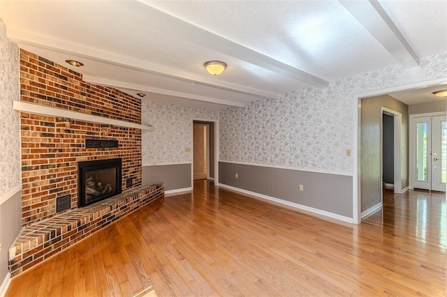 21509 Rockwell Dr, Lebanon, MO 65536 - unfurnished living room with wood finished floors, a wainscoted wall, beamed ceiling, and a fireplace