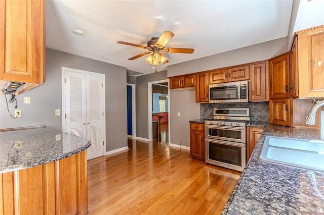 21509 Rockwell Dr, Lebanon, MO 65536 - kitchen with stainless steel appliances, a sink, light wood-style floors, brown cabinets, and tasteful backsplash