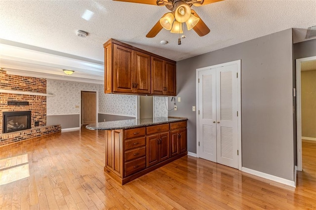 21509 Rockwell Dr, Lebanon, MO 65536 - kitchen featuring light wood-style floors, brown cabinets, ceiling fan, a textured ceiling, and wallpapered walls