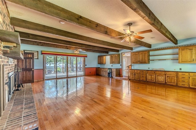 21509 Rockwell Dr, Lebanon, MO 65536 - unfurnished living room with light wood-type flooring, a brick fireplace, plenty of natural light, beamed ceiling, and ceiling fan