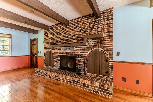 21509 Rockwell Dr, Lebanon, MO 65536 - unfurnished living room featuring a textured ceiling, wood finished floors, a fireplace, beam ceiling, and baseboards