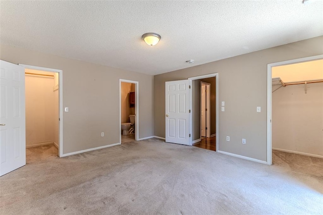 21509 Rockwell Dr, Lebanon, MO 65536 - unfurnished bedroom featuring a walk in closet, a closet, carpet floors, and a textured ceiling