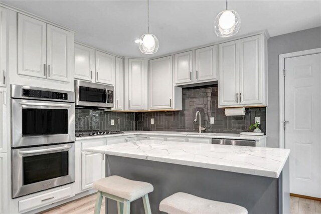 402 Glan Tai Dr, Manchester, MO 63011 - kitchen featuring stainless steel appliances, a sink, light wood-style floors, and a kitchen bar