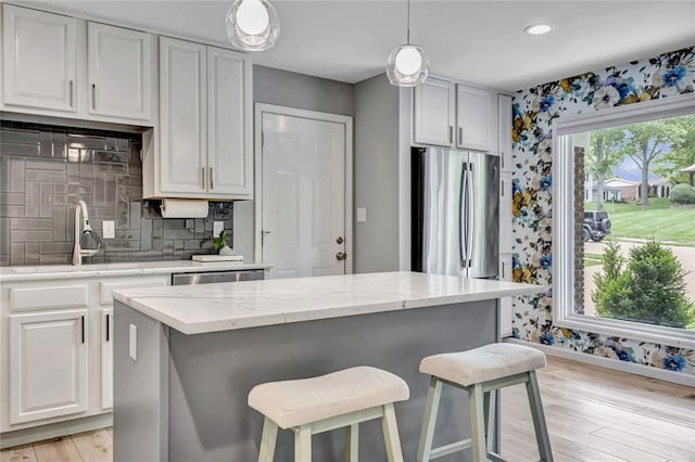 402 Glan Tai Dr, Manchester, MO 63011 - kitchen with a sink, baseboards, wallpapered walls, light wood-style flooring, and a breakfast bar