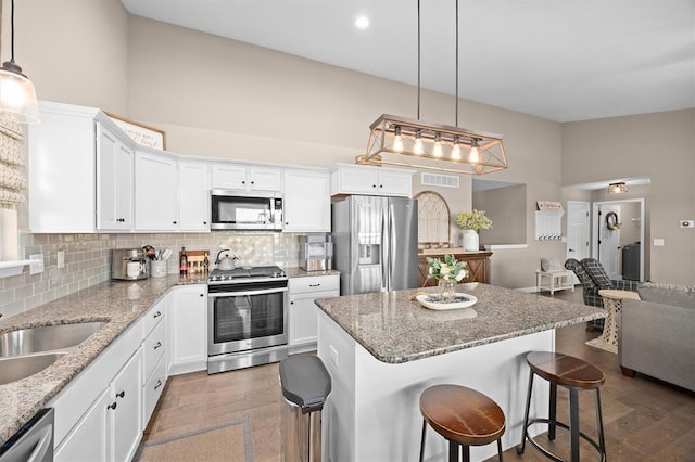 536 W 5th St, Saint Jacob, IL 62281 - kitchen with stainless steel appliances, white cabinetry, a breakfast bar, backsplash, and a high ceiling