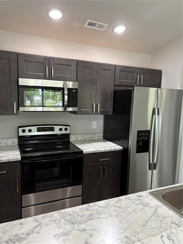 10 Jaybird Ct, Montgomery City, MO 63361 - kitchen featuring appliances with stainless steel finishes, light stone counters, a sink, and dark brown cabinetry