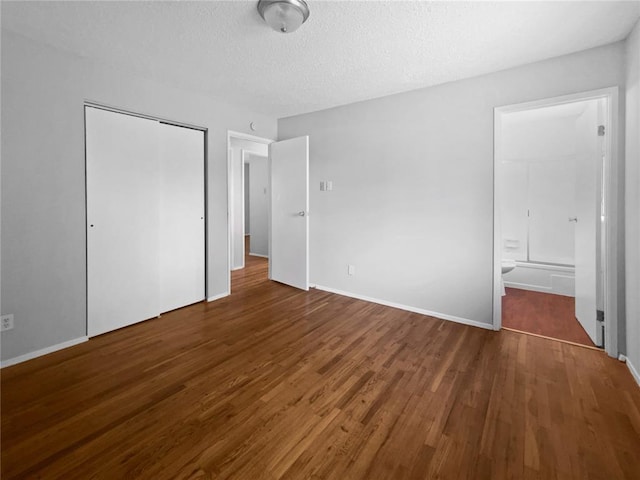 2540 Courtyard Pl, Florissant, MO 63031 - unfurnished bedroom featuring wood finished floors, a closet, connected bathroom, a textured ceiling, and baseboards