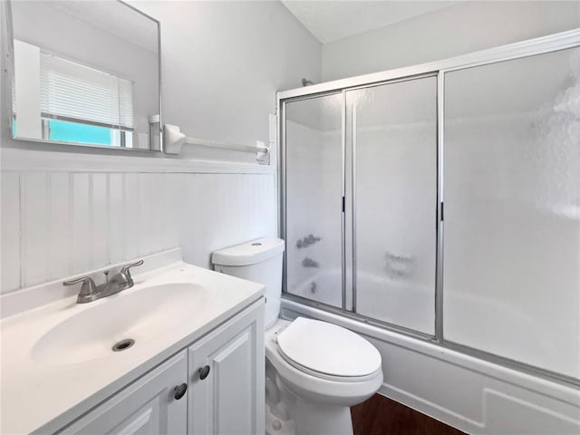 2540 Courtyard Pl, Florissant, MO 63031 - bathroom with bath / shower combo with glass door, vanity, a wainscoted wall, and toilet