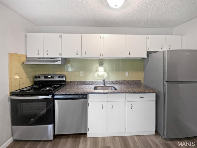 2540 Courtyard Pl, Florissant, MO 63031 - kitchen with appliances with stainless steel finishes, range hood, a sink, wood finished floors, and white cabinetry