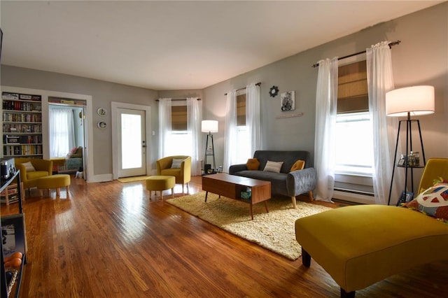 living area with wood finished floors, plenty of natural light, and baseboard heating