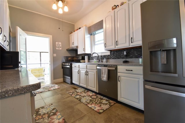 kitchen with appliances with stainless steel finishes, white cabinetry, tasteful backsplash, a sink, and under cabinet range hood