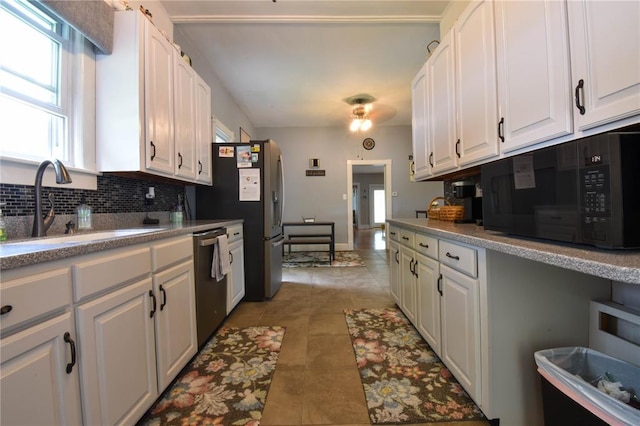 kitchen featuring appliances with stainless steel finishes, a sink, white cabinetry, tasteful backsplash, and light tile patterned flooring