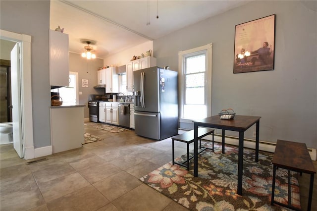 kitchen featuring appliances with stainless steel finishes, ceiling fan, a baseboard radiator, white cabinets, and a sink