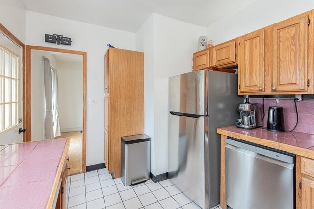 5156 Christy Ave, Saint Louis, MO 63116 - kitchen with appliances with stainless steel finishes, tile countertops, light tile patterned flooring, and decorative backsplash