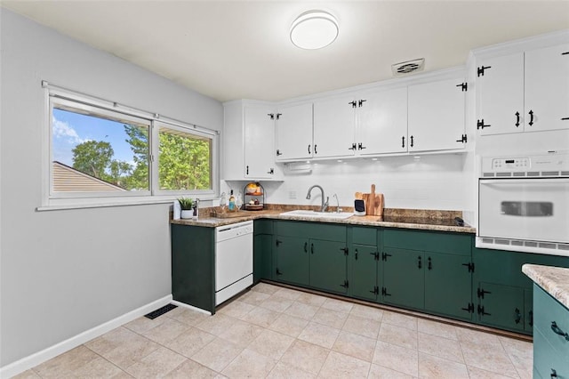 kitchen featuring white appliances, a sink, green cabinets, white cabinetry, and baseboards