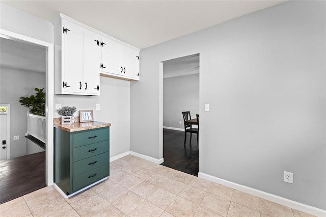 kitchen featuring white cabinets, baseboards, light countertops, and light tile patterned floors
