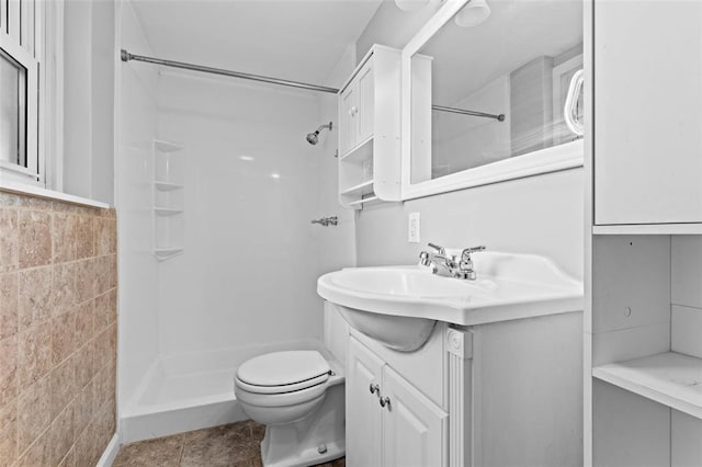full bath with a shower, tile walls, vanity, and toilet