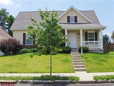 view of front of home with covered porch, stairway, and a front lawn