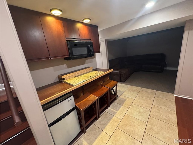 2828 Rutger St, Saint Louis, MO 63104 - kitchen featuring light carpet, light tile patterned flooring, dark countertops, and black microwave