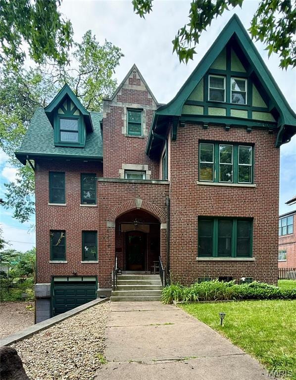 6214 Pershing Ave, Saint Louis, MO 63130 - tudor-style house featuring brick siding, a garage, and a front yard