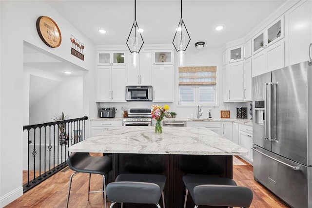 1017 Kilderkin Way, Saint Charles, MO 63301 - kitchen featuring stainless steel appliances, a sink, a kitchen island, a breakfast bar area, and light wood-type flooring