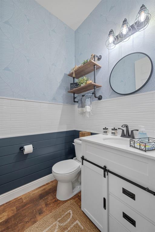 1017 Kilderkin Way, Saint Charles, MO 63301 - half bath featuring toilet, wood finished floors, vanity, wainscoting, and wallpapered walls