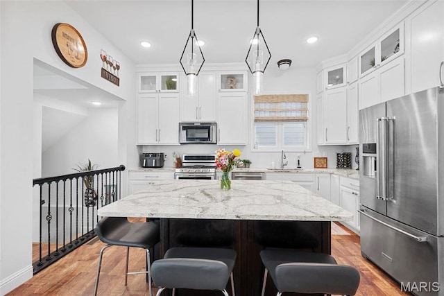 1017 Kilderkin Way, Saint Charles, MO 63301 - kitchen featuring appliances with stainless steel finishes, a sink, a kitchen island, a breakfast bar, and light wood-type flooring