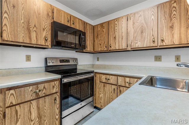 101 Carnegie Ct, Valley Park, MO 63088 - kitchen featuring black microwave, stainless steel range with electric cooktop, light countertops, a sink, and brown cabinets