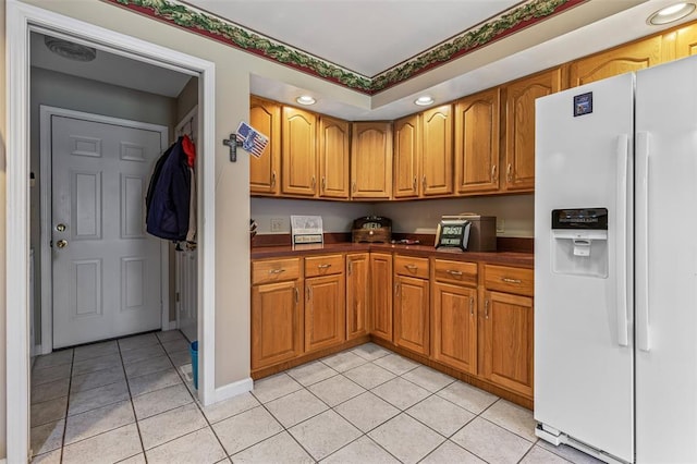 303 Holly Tree Ln, Farmington, MO 63640 - kitchen with white refrigerator with ice dispenser, dark countertops, light tile patterned flooring, brown cabinets, and recessed lighting