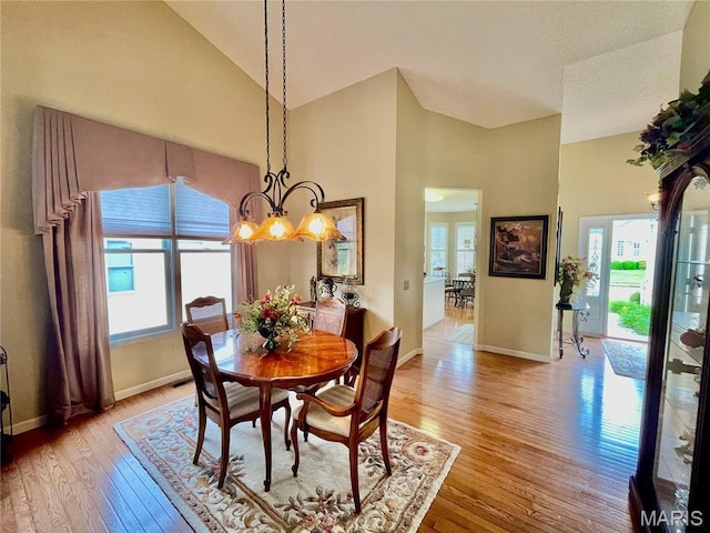 2087 Hawks Landing Dr, Lake St Louis, MO 63367 - dining room featuring light wood-type flooring, plenty of natural light, a chandelier, and high vaulted ceiling